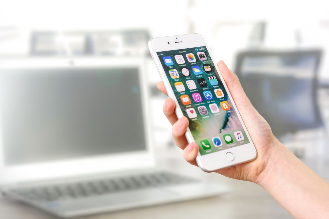 手持iPhone,屏幕显示应用图标